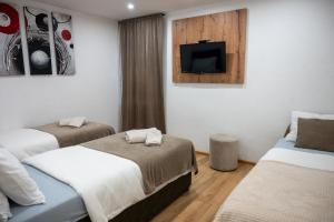 a room with two beds and a tv on the wall at Apartmani Prestige in Gornji Vakuf