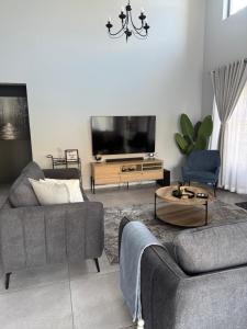 a living room with two couches and a flat screen tv at Belo Villa Clarens in Clarens