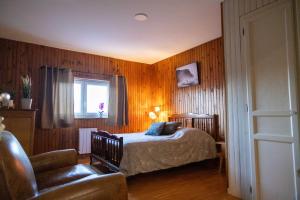 ein Schlafzimmer mit einem Bett, einem Stuhl und einem Fenster in der Unterkunft Appart Hôtel Ambert in Marsac-en-Livradois