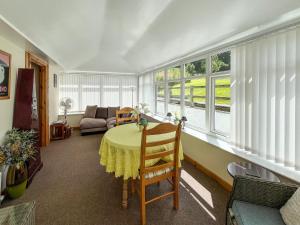 a room with a table and a couch and windows at Uk47549 - Carty Cottage in Newton Stewart