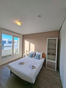 a bedroom with a large white bed with a window at Séjours & Affaires La Rochelle Les Minimes in La Rochelle