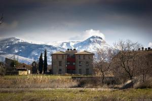 ein Gebäude vor einem Berg mit Bergen im Hintergrund in der Unterkunft Apartamentos Turisticos Rio Gallego in Fontellas