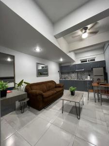 a living room with a brown couch and a kitchen at AR SUITES DEPARTAMENTO CENTRO 3 in Zamora de Hidalgo