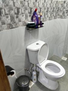 a bathroom with a toilet and a shelf on the wall at Urbanza Haven Nakuru in Nakuru +7 photos