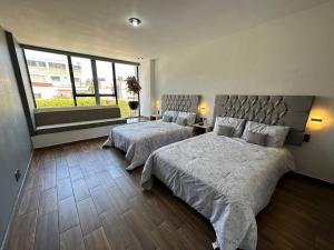 a bedroom with two beds and a large window at AR Suites 2 La Calzada in Zamora de Hidalgo