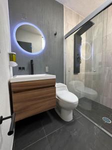 a bathroom with a toilet and a sink and a mirror at AR Suites 2 La Calzada in Zamora de Hidalgo