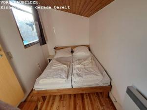 a small bed in a small room with a wooden floor at Wald Chalet Nr 4 in Kellenhusen +4 photos