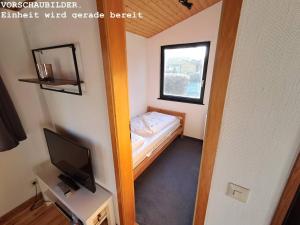 a small room with a small bed and a television at Wald Chalet Nr 4 in Kellenhusen