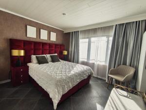 a bedroom with a large bed with a red headboard at Lazy Olives in Tongeren +91 photos