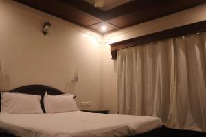 a bedroom with a bed with white sheets and a window at Sacred River Houseboats in Alleppey