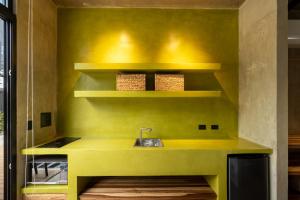a yellow kitchen with a sink and shelves at The Sunset Deck in Jacó