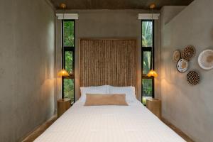 a bedroom with a large white bed with two windows at The Sunset Deck in Jacó +45 photos