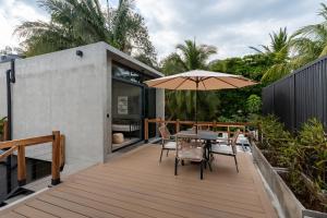 a wooden deck with a table and an umbrella at The Sunset Deck in Jacó