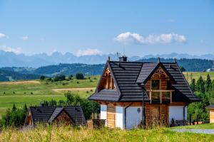 a house in a field with mountains in the background at Osada Dursztyn- Przystanek Podhale in Białka Tatrzańska