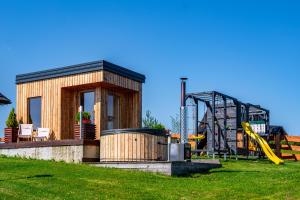 a small wooden cabin with a playground in a field at Osada Dursztyn- Przystanek Podhale in Białka Tatrzańska