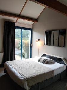 a bedroom with a large bed with a large window at Les Dineux Village in Trémeur