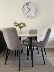 a table with two chairs and a clock on the wall at Mountain Oak 2 Jindabyne in Jindabyne