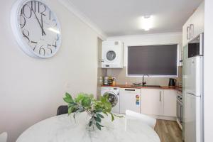 a kitchen with a table and a large clock on the wall at Mountain Oak 2 Jindabyne in Jindabyne +7 photos