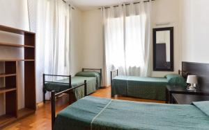 ein Hotelzimmer mit drei Betten und einem Spiegel in der Unterkunft Ogbay Backpackers Haven in Rom