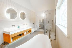 a bathroom with a sink and a toilet and mirrors at Seahenge in Brancaster +46 photos