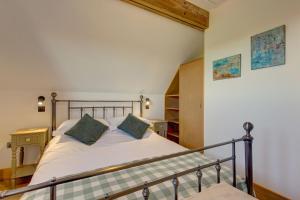 a bedroom with a bed with white sheets and green pillows at Wallower in Harpley
