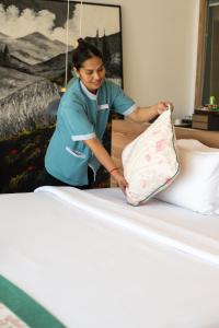 a woman is putting a pillow on a bed at The Snowbell Hotel & Spa at The Bridge in Phnom Penh