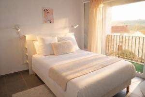 a bedroom with a white bed with a large window at Le Candy- Appartement de charme à Digoin in Digoin