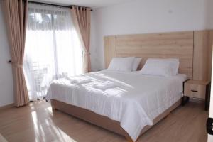 a bedroom with a large white bed with a large window at Hotel Campestre Kambra in Garagoa