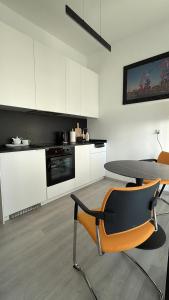 a kitchen with white cabinets and a table and chairs at Hanza Tower Level XV Signature in Szczecin