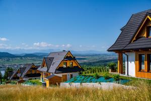 a row of houses on a hill with mountains in the background at Osada Widokówka- Przystanek Podhale in Czorsztyn