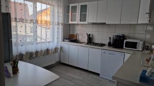 a kitchen with white cabinets and a sink and a window at Cabana Angela in Râșca