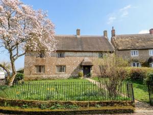an old stone house with a gate in front of it at Manor Cottage in Ilminster