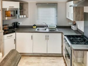 a kitchen with white cabinets and a sink at 54 Beach Retreat in Burnham on Sea +9 photos