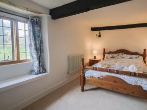 a bedroom with a wooden bed and a window at Manor Cottage in Ilminster