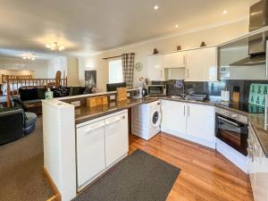 a kitchen with white cabinets and a living room at Uk47549 - Carty Cottage in Newton Stewart +4 photos