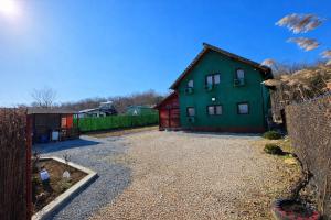 a green house with a gravel driveway at Casa delta verde in Mahmudia