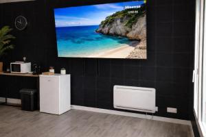 a flat screen tv hanging on a wall with a beach at Suite Cinéma #7#- Jacuzzi in Roubaix