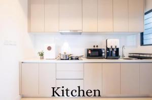 a kitchen with white cabinets and a microwave at Skyline Luxury Suite KlCC &TRX View in Kuala Lumpur