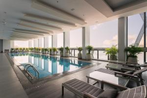 a large swimming pool with chairs and a table at The Snowbell Hotel & Spa at The Bridge in Phnom Penh