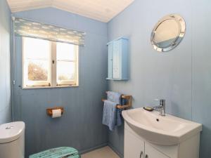 a blue bathroom with a sink and a mirror at The Cabin in Cawsand