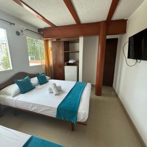 a bedroom with a bed with blue pillows and a television at Hotel Rodadero Relax in Gaira +33 photos