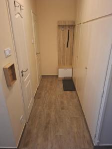 an empty hallway with a shower and a wooden floor at Dombó apartman in Dombóvár