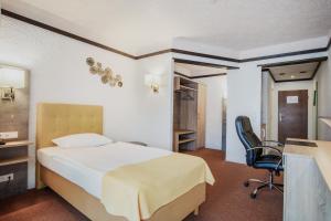 a bedroom with a bed and a desk and a chair at CONTEL Hotel in Koblenz