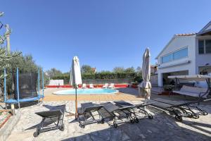Eine Gruppe von Stühlen und Sonnenschirmen neben einem Pool in der Unterkunft Polaca in Kakma