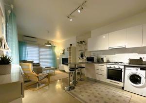 a kitchen with white cabinets and a table and chairs at MyGuest Cornelius 70 , 1-Bedroom Luxury Apartment in Iskele