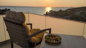 a table with a bowl of fruit and a chair on a balcony at Sunset Bay Casa in Dolac