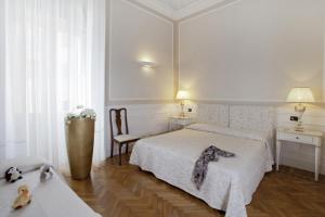 a white bedroom with a bed and two tables and a chair at Palazzo Lombardo in Florence +27 photos
