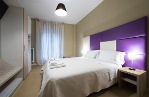 um quarto com uma cama grande e uma cabeceira de cama roxa em Tiffany Rooms em Milão