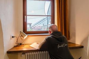 a man sitting at a desk looking out a window at Casa Anastasia with private patio by GardaDoma in Brenzone sul Garda