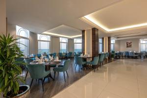 a dining room with tables and chairs and windows at Braiden Hotel in Al Jubail